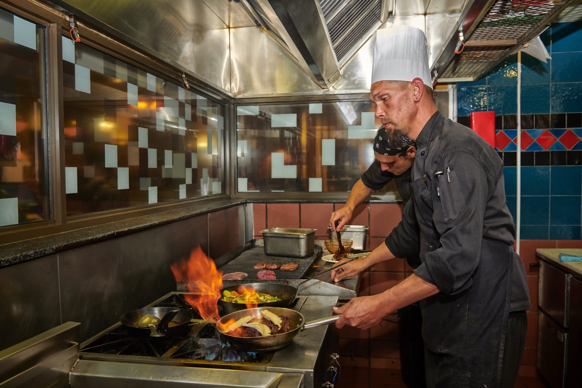 Chefs flame-grilling steaks in the Beef Baron Grillhouse kitchen at Frontier Inn, Bethlehem