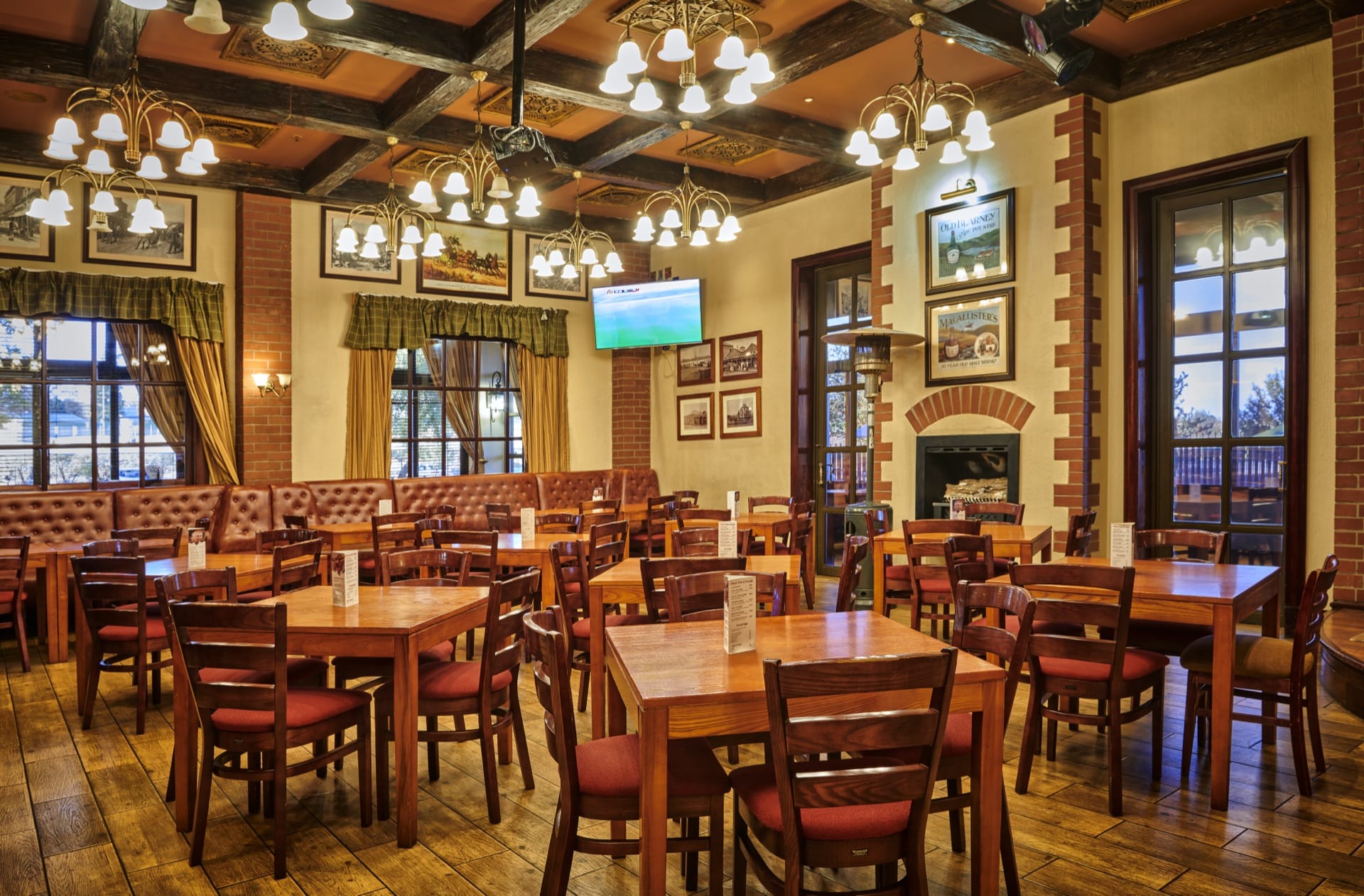 The Coachman's Saloon dining room with timber tables and a brick fireplace at Frontier Inn, Bethlehem