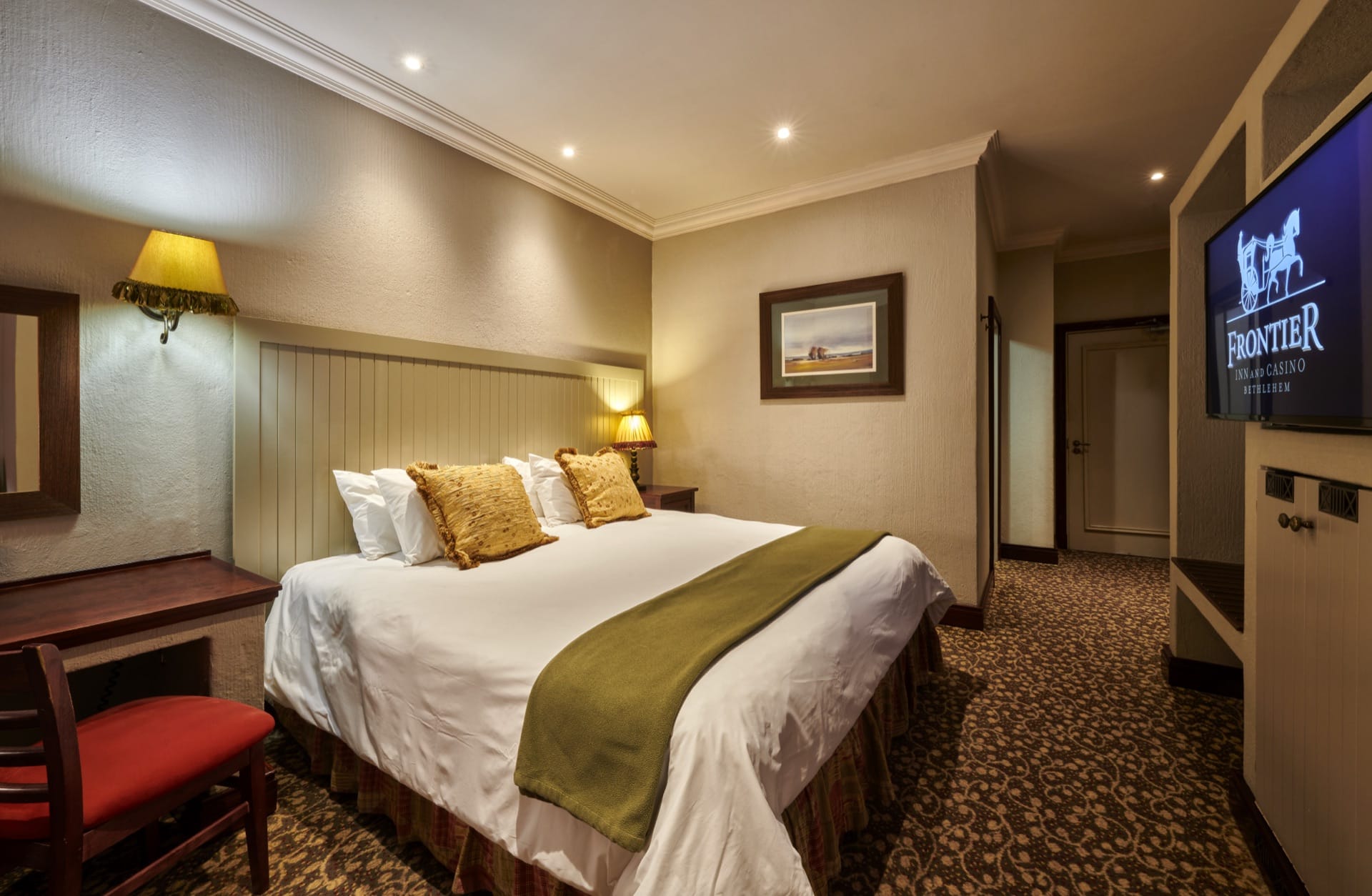 A comfortable hotel room with king bed and green throw at Frontier Inn, a 3-star hotel in Bethlehem, Free State