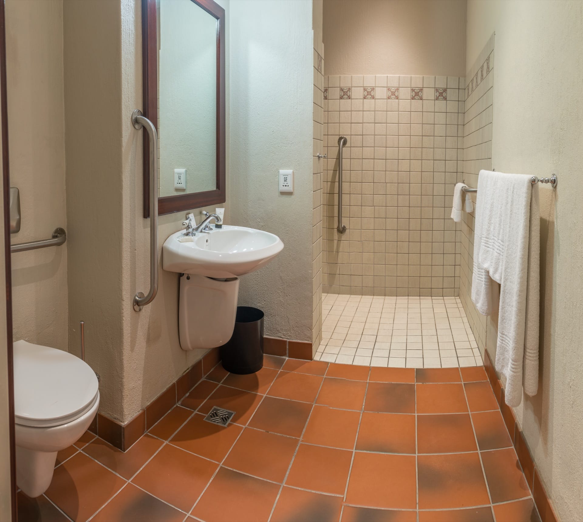 Accessible bathroom with grab rails, wall-hung basin and level-entry shower at Frontier Inn, Bethlehem