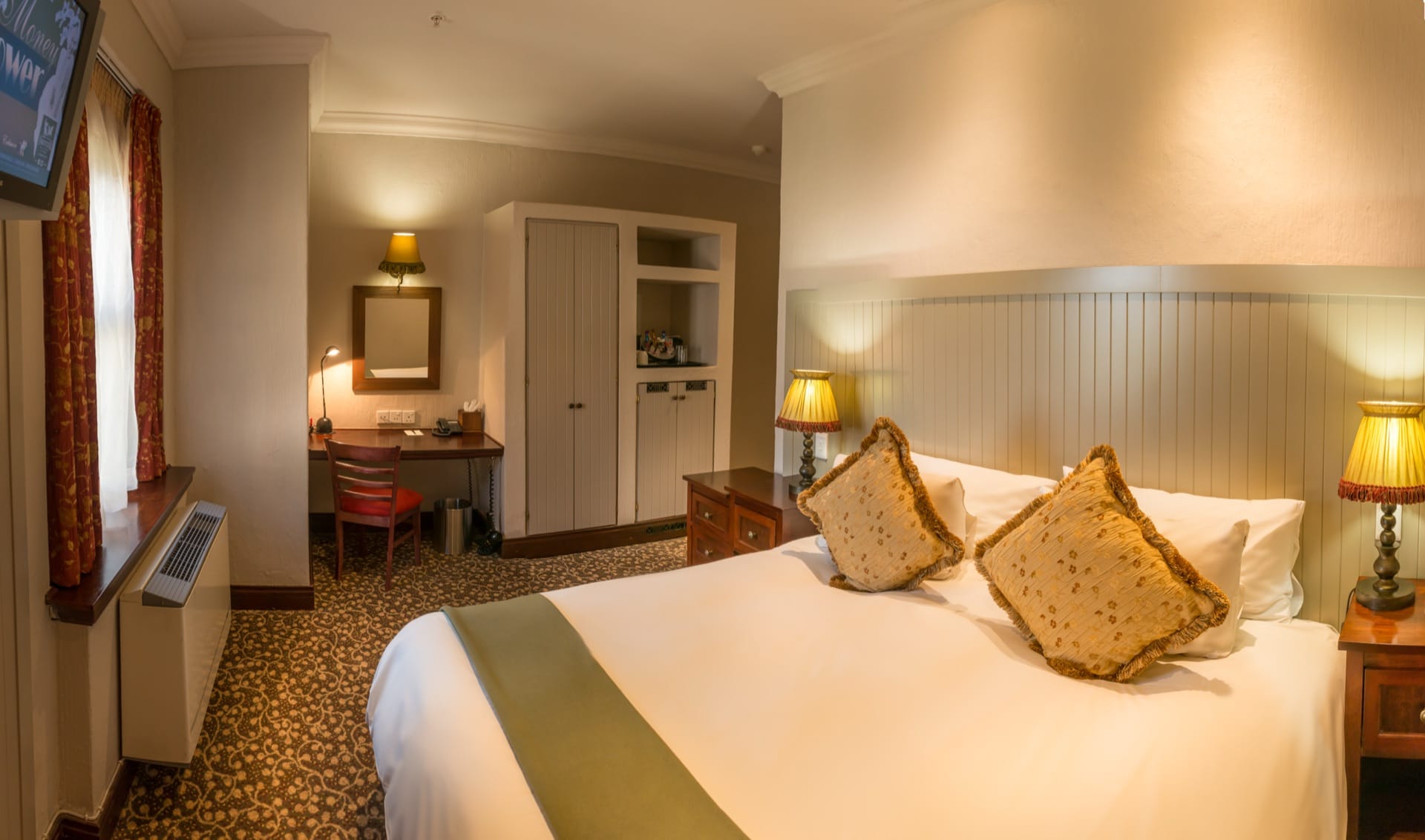 Accessible room with bed, bedside lamps and desk at Frontier Inn, Bethlehem