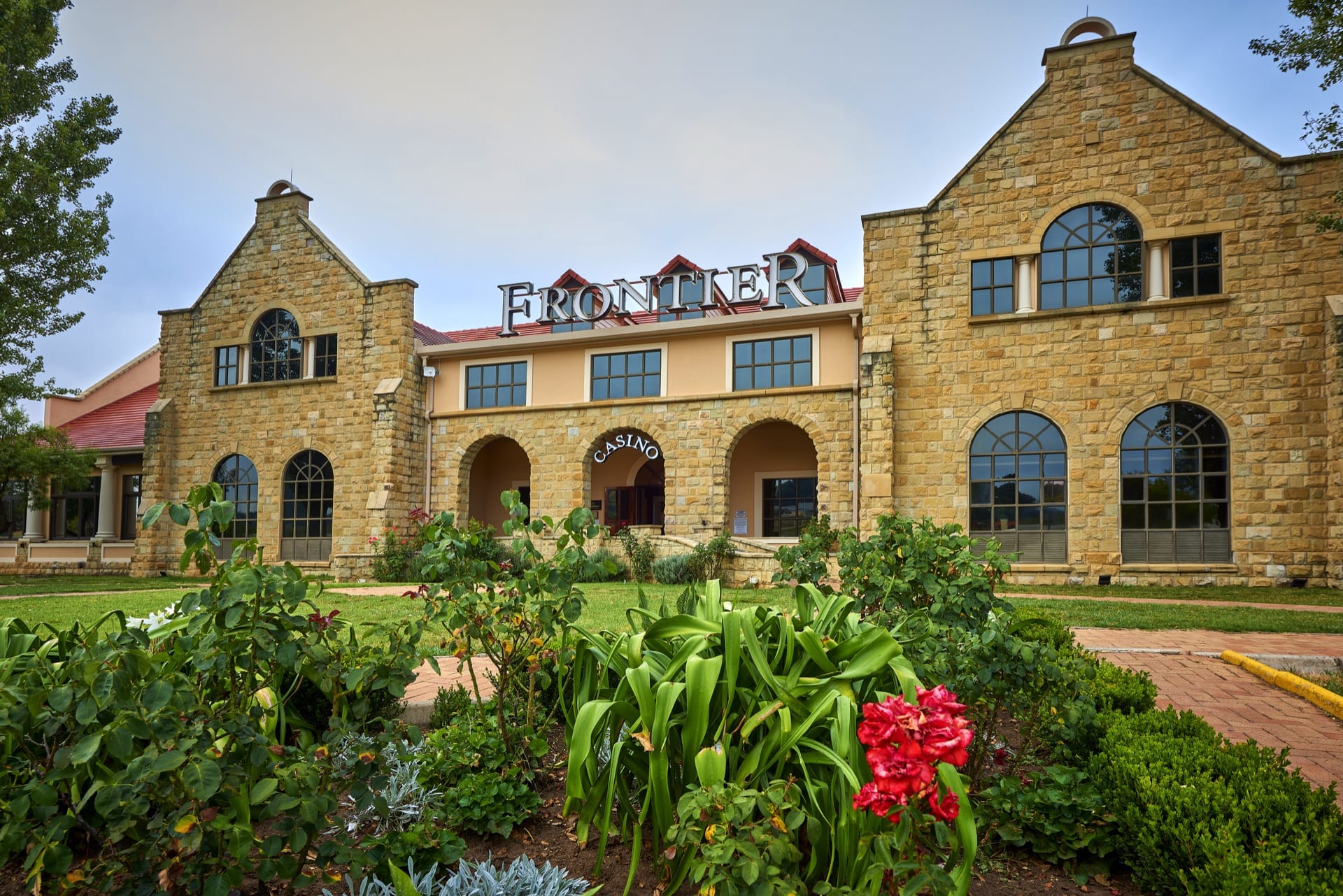 Sandstone building with casino signage above landscaped gardens at Frontier Inn, Bethlehem